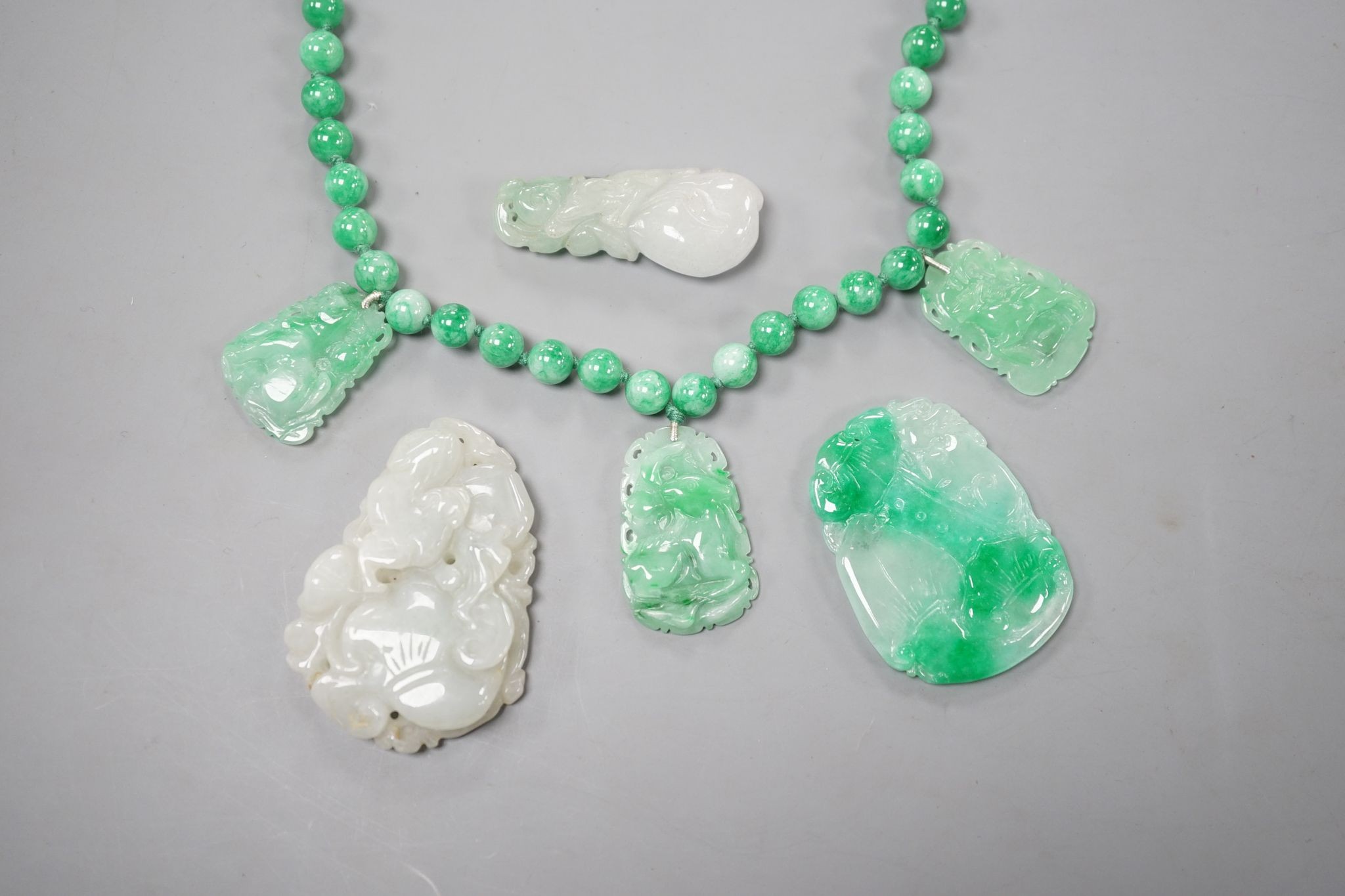 A jade bead necklace hung with three jade carvings, 49cm and three other jade carvings.